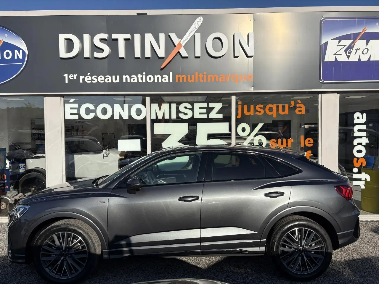 Profil droit d'un Audi Q3 Sportback gris Daytona avec jantes 20 branches en V et badge S line visible sur l'aile avant.