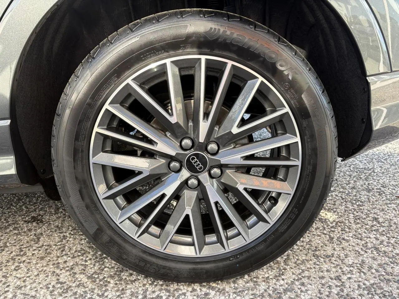 Gros plan sur la jante en aluminium 20 branches en V gris contrasté du côté gauche d'un Audi Q3 Sportback gris Daytona.