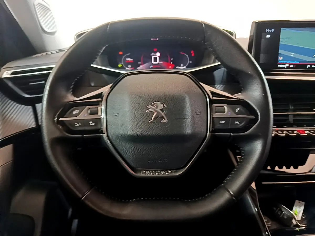 Volant cuir noir de Peugeot 2008 2021 avec commandes intégrées et tableau de bord numérique en arrière-plan.