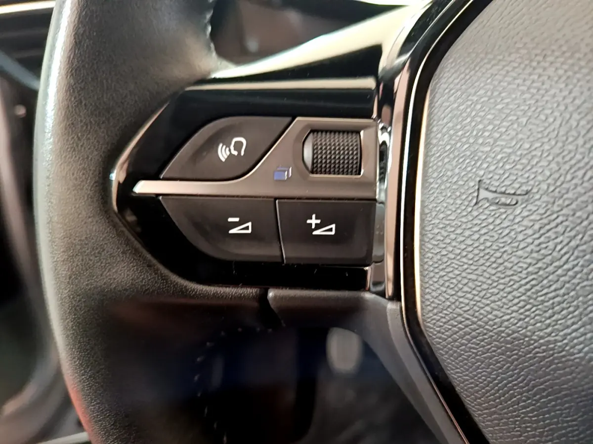 Gros plan sur les commandes gauche du volant cuir noir du Peugeot 2008 gris clair, version PureTech 130 S&S Allure Business.