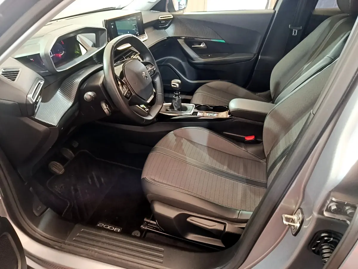 Intérieur côté conducteur du Peugeot 2008 gris clair 2021, volant cuir, tableau de bord numérique et boîte manuelle.