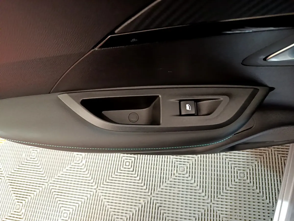 Détail de la poignée intérieure côté gauche d'une Peugeot 2008 gris clair avec bouton de verrouillage.