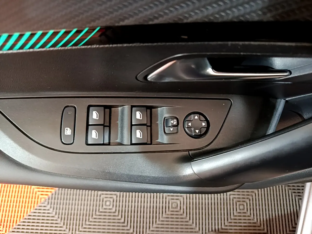 Gros plan sur la commande des vitres et rétroviseurs côté gauche d'une Peugeot 2008 gris clair, intérieur noir.