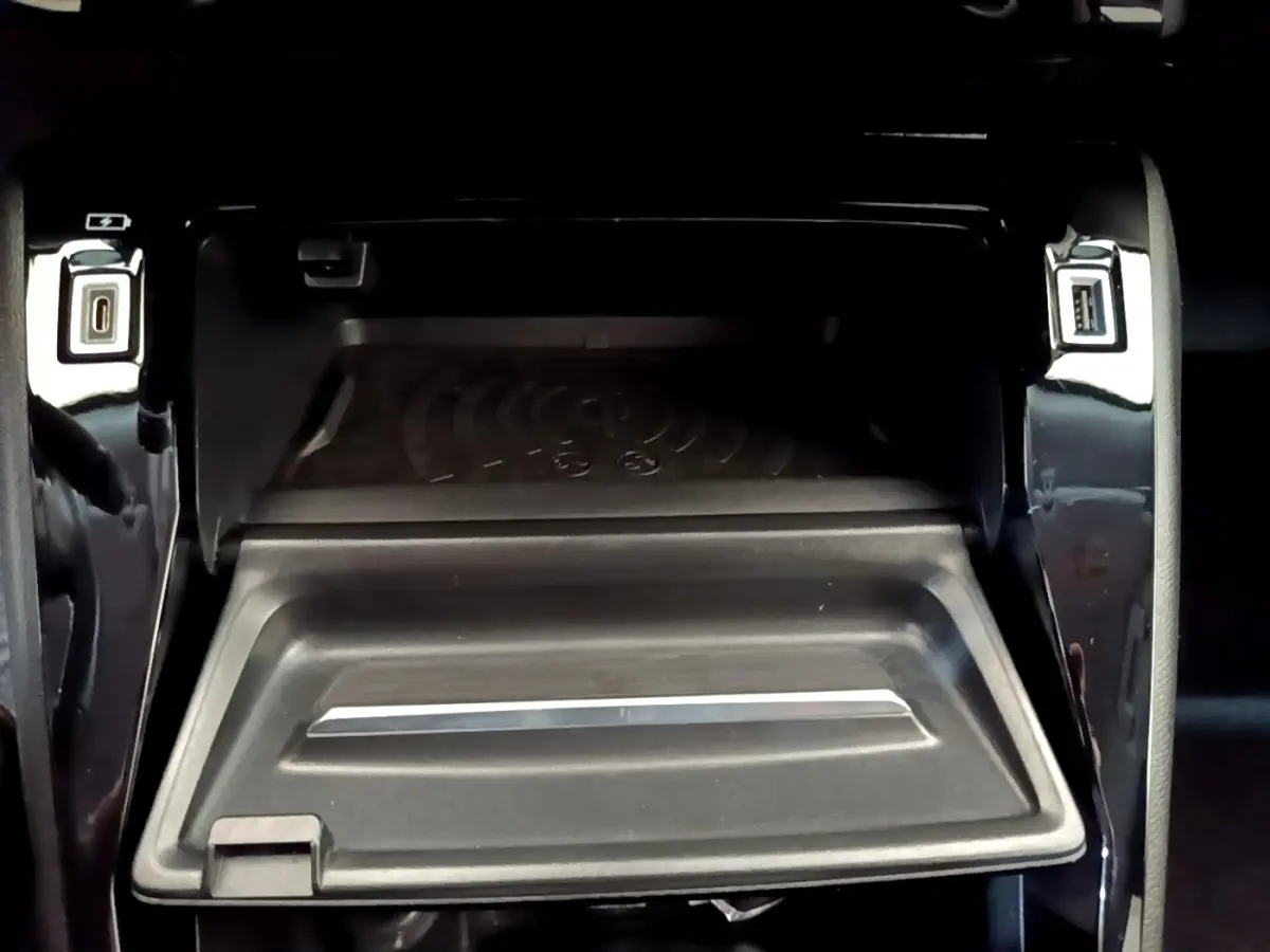 Vue rapprochée de la console centrale noire du Peugeot 2008 2021, montrant le compartiment de recharge sans fil et ports USB.