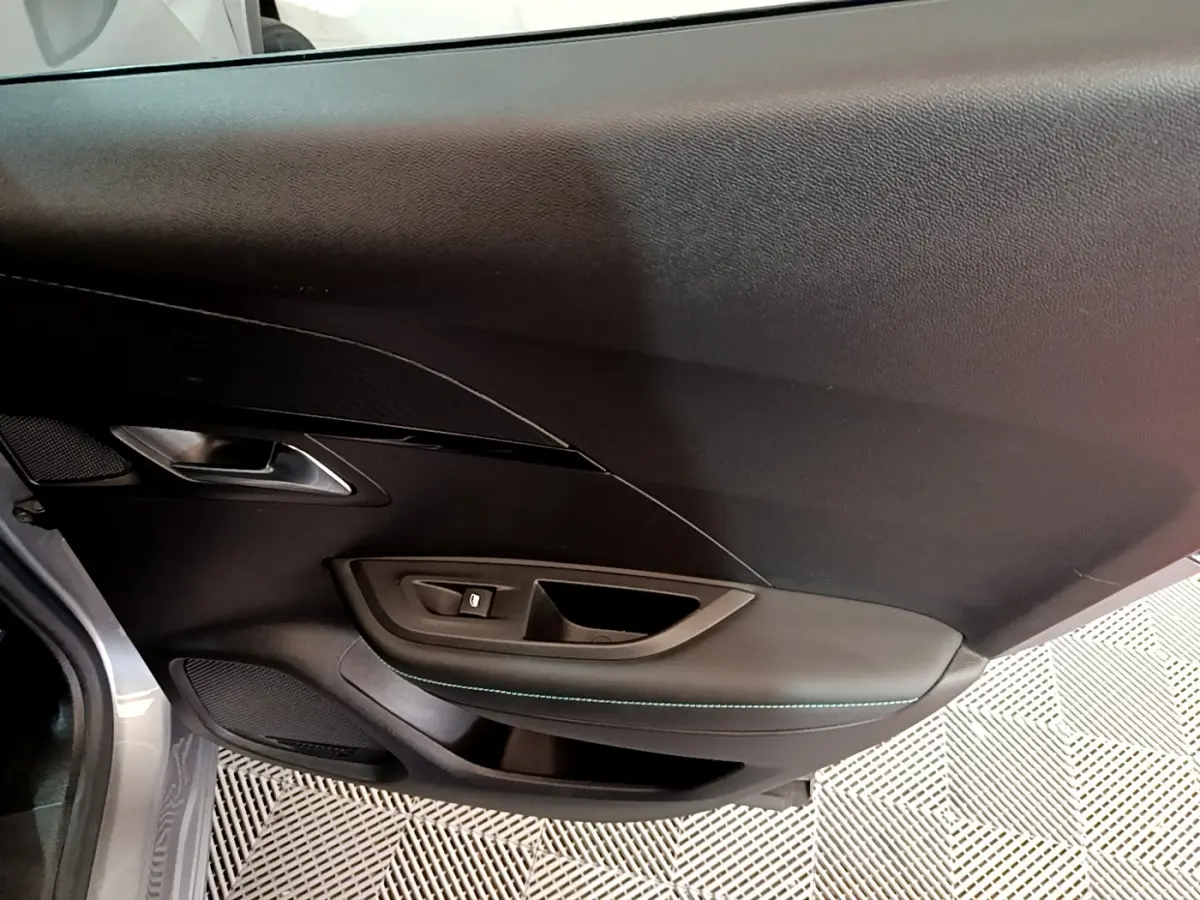 Vue intérieure du panneau de porte côté gauche gris foncé avec surpiqûres vertes du Peugeot 2008 gris clair 2021.