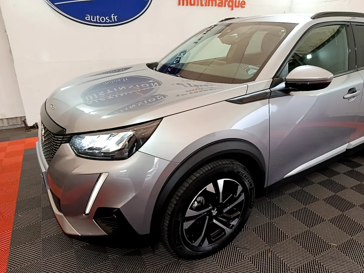 Peugeot 2008 gris clair vue 3/4 avant droit, avec phares LED et jantes noires distinctives.