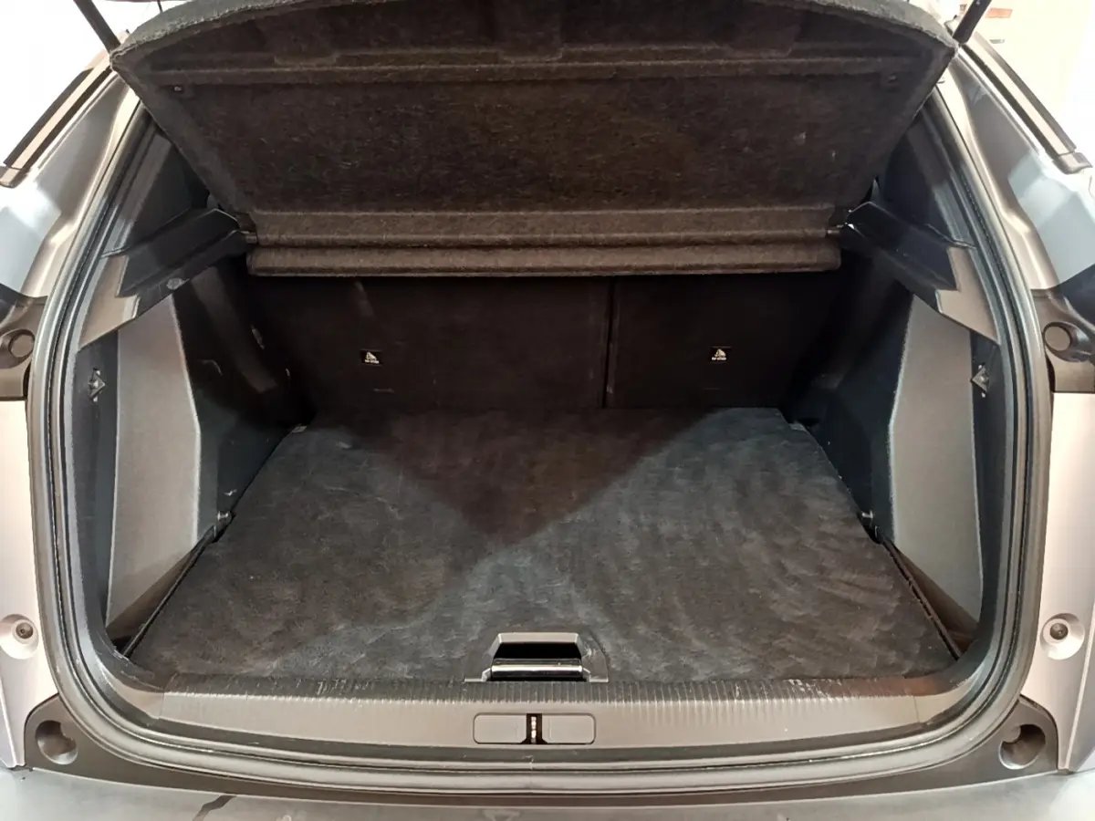 Coffre ouvert du Peugeot 2008 gris clair, vue arrière montrant l'espace de chargement vide et la tablette de séparation.