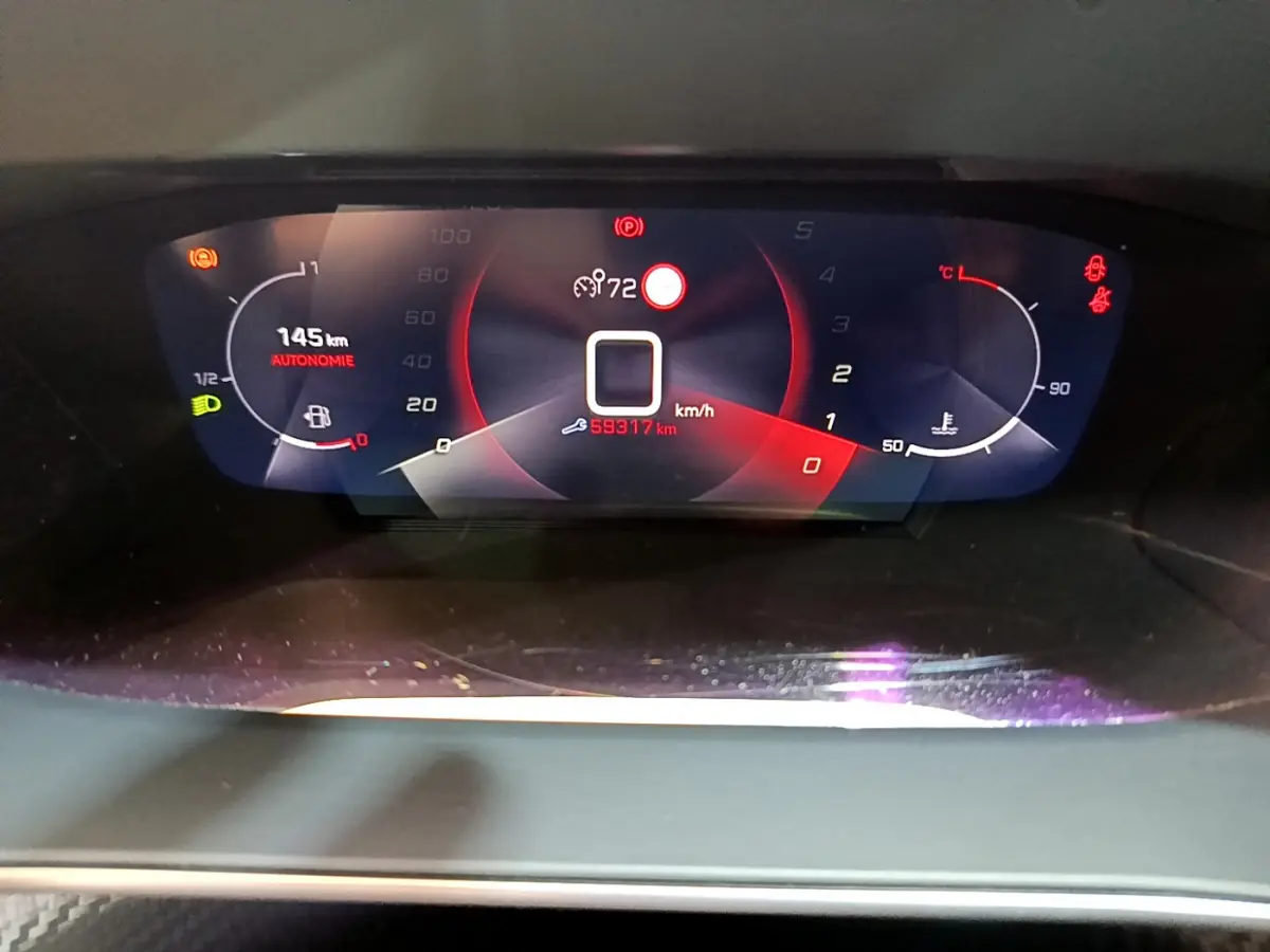 Tableau de bord numérique du Peugeot 2008 PureTech 130, affichant la vitesse et autonomie, en vue frontale rapprochée.