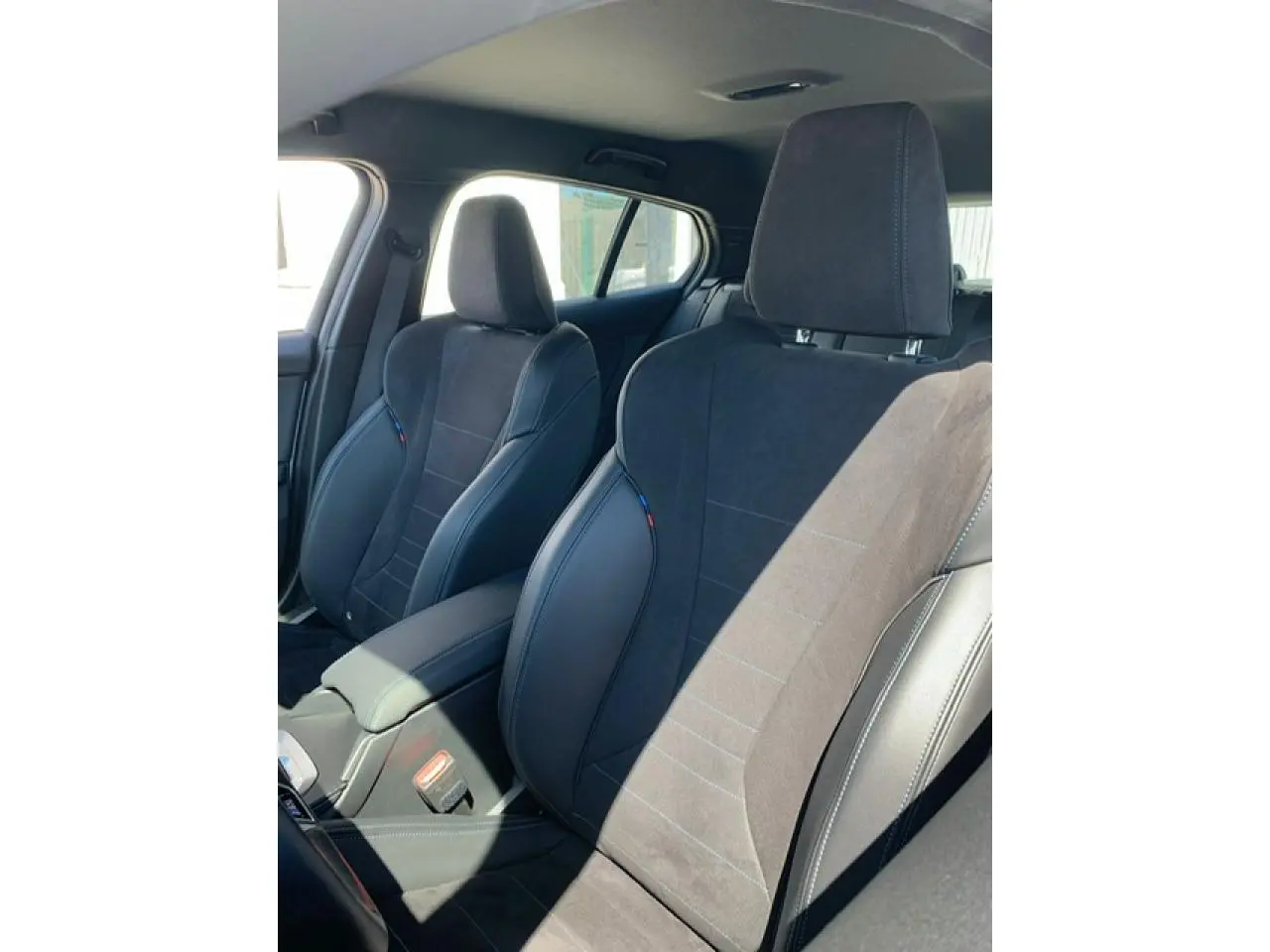 Gros plan sur les sièges avant sport en Alcantara noir avec surpiqûres bleues de la BMW Série 1 F70 M Sport.