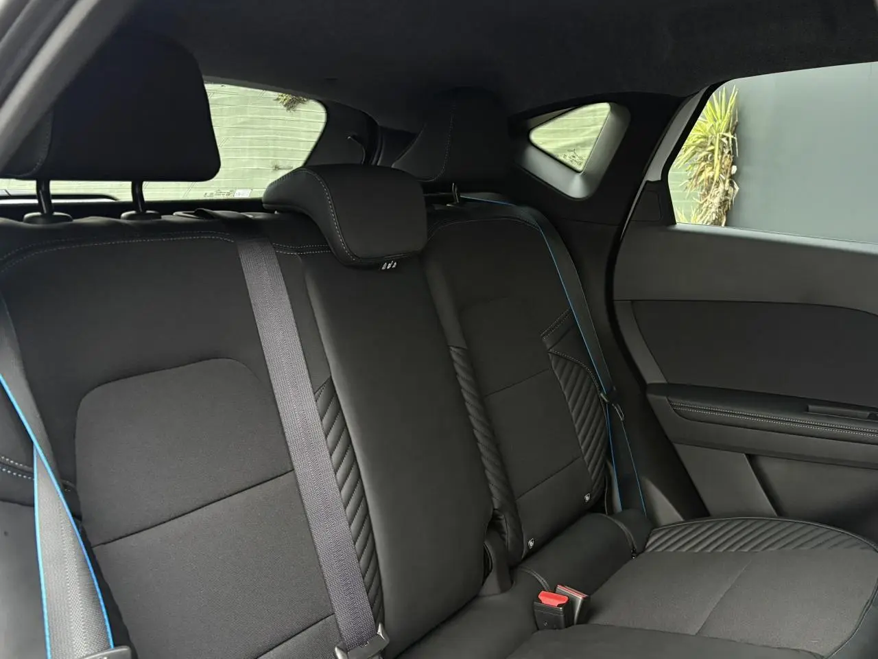 Vue intérieure sur la banquette arrière noire avec surpiqûres bleues du Renault Captur Blanc Nacré 2025 Esprit Alpine.