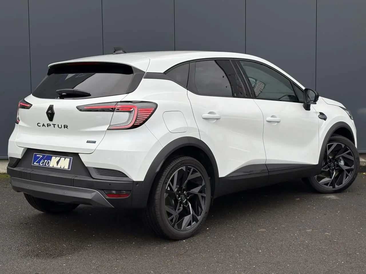 Vue 3/4 arrière droite d'un Renault Captur blanc nacré avec jantes noires et vitres surteintées.