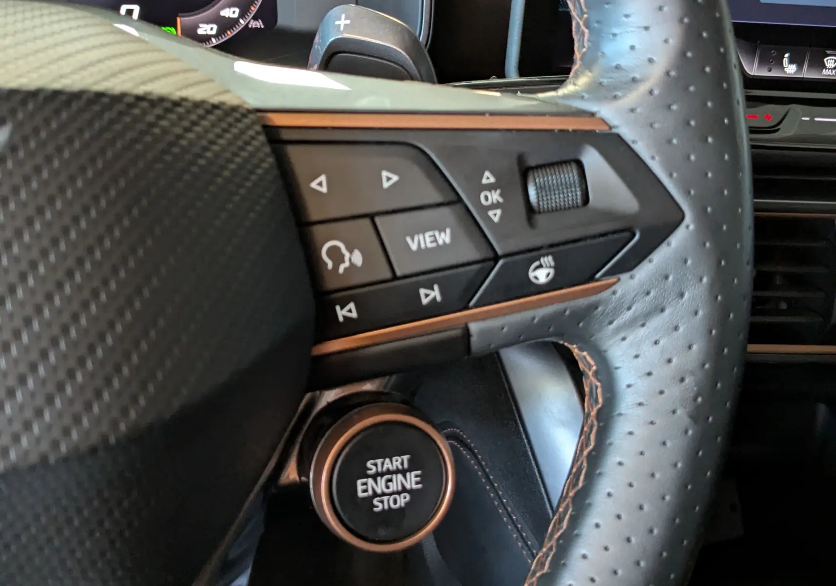 Gros plan sur le volant en cuir perforé avec commandes multifonctions et bouton start/stop du CUPRA Formentor gris magnétique.