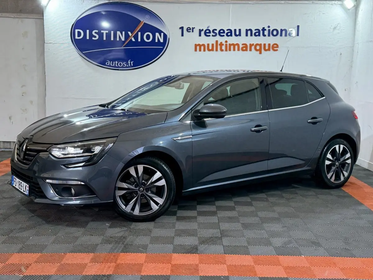 Renault Mégane Intens gris foncé vue de profil droit en intérieur, avec jantes alliage et phares LED allumés.