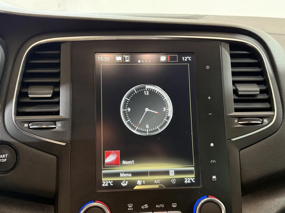 Écran tactile central affichant une horloge digitale dans le tableau de bord d'une Renault Mégane gris foncé, vue de face.