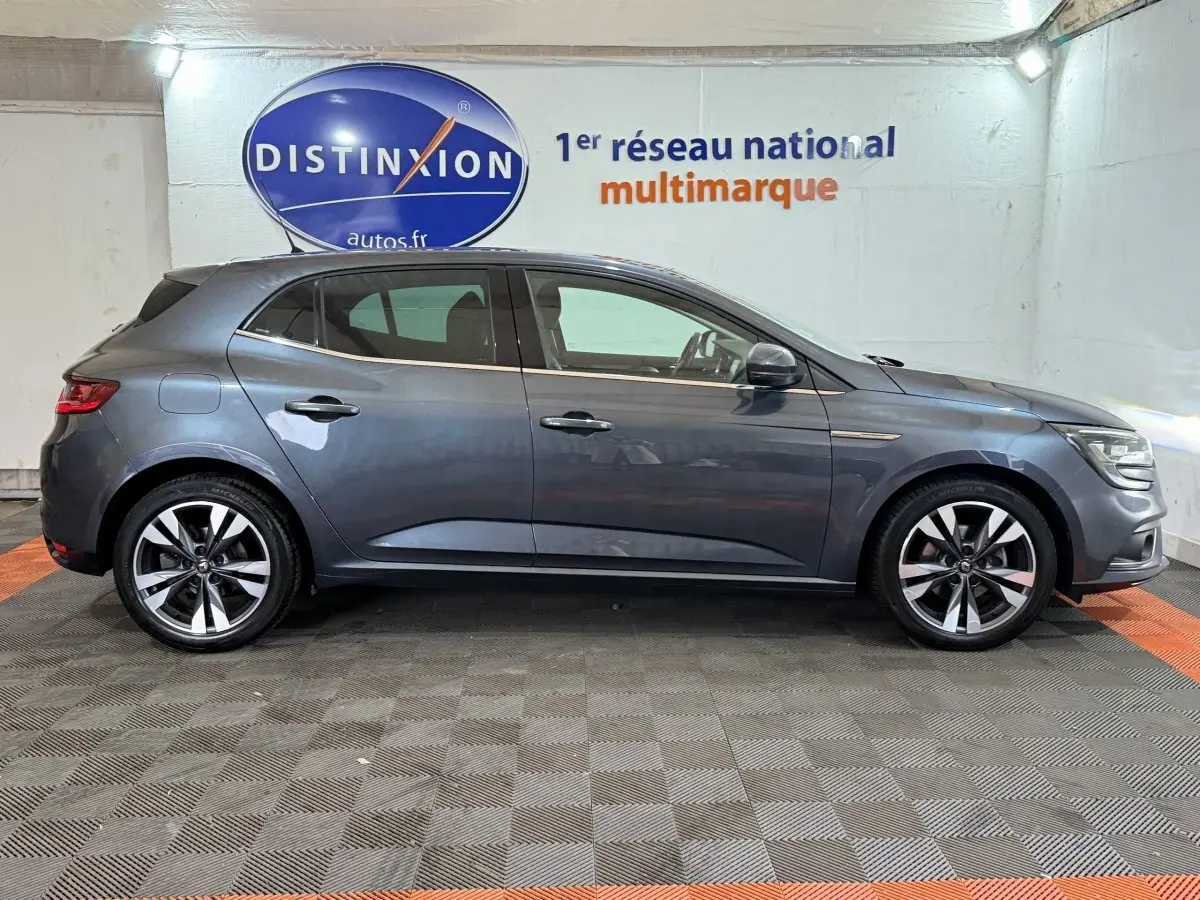 Profil côté gauche d'une Renault Mégane Intens gris foncé de 2019, avec jantes alliage et feux avant allumés.