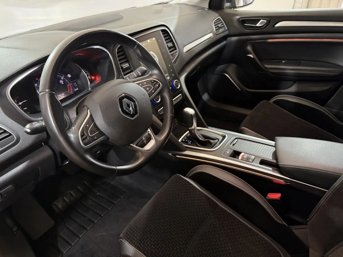 Vue intérieure côté conducteur de la Renault Mégane Intens 2019, volant cuir et console centrale avec boîte auto.