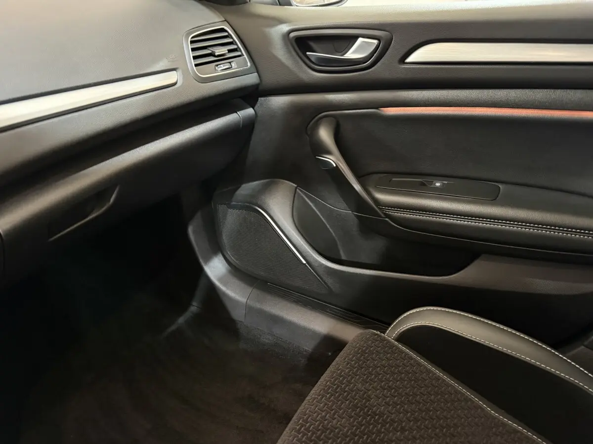 Intérieur côté passager de la Renault Mégane gris foncé, avec porte en cuir noir et détails de finition.