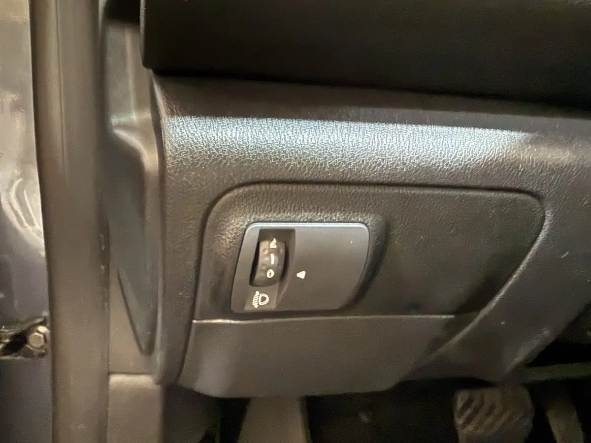 Détail du réglage des phares sur le tableau de bord noir de la Renault Mégane gris foncé, vue côté conducteur.