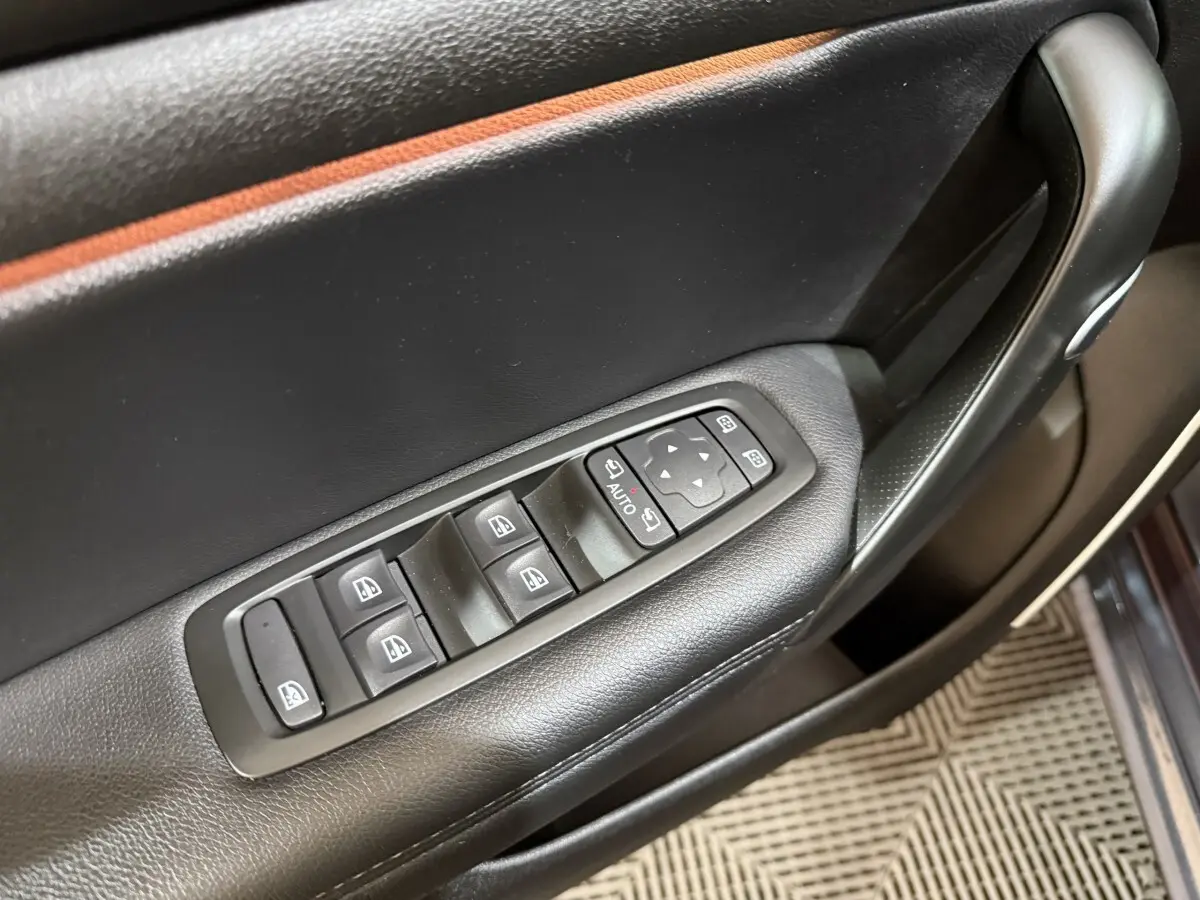 Gros plan sur les commandes des lève-vitres et rétroviseurs côté conducteur d’une Renault Mégane gris foncé 2019.