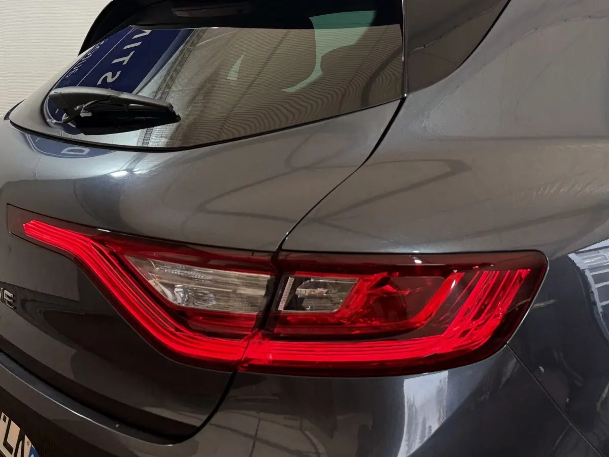 Gros plan sur le feu arrière droit rouge et blanc d’une Renault Mégane gris foncé de 2019.