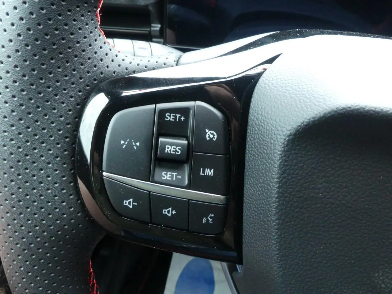 Gros plan sur les commandes du volant perforé noir du Ford Puma 2025, avec boutons de régulateur et volume sonore.