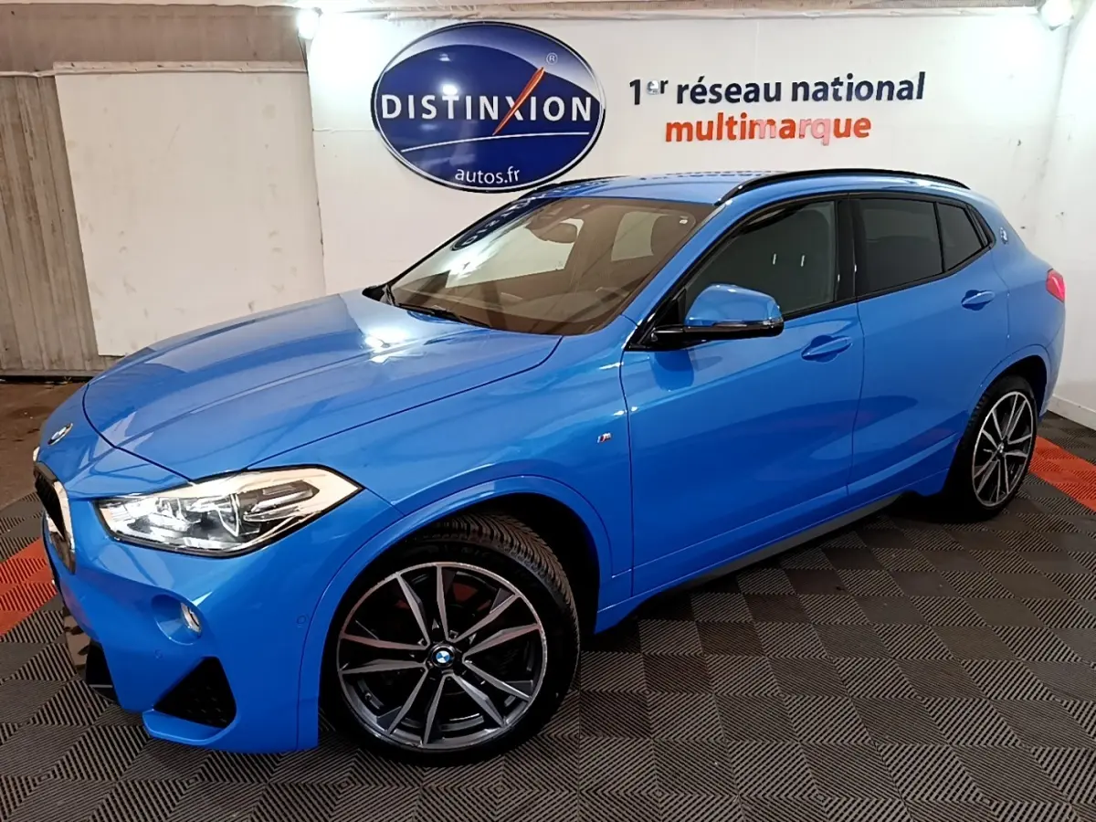 BMW X2 sDrive20i M Sport bleu en vue 3/4 avant droit, avec jantes sport et vitres teintées, intérieur beige visible.
