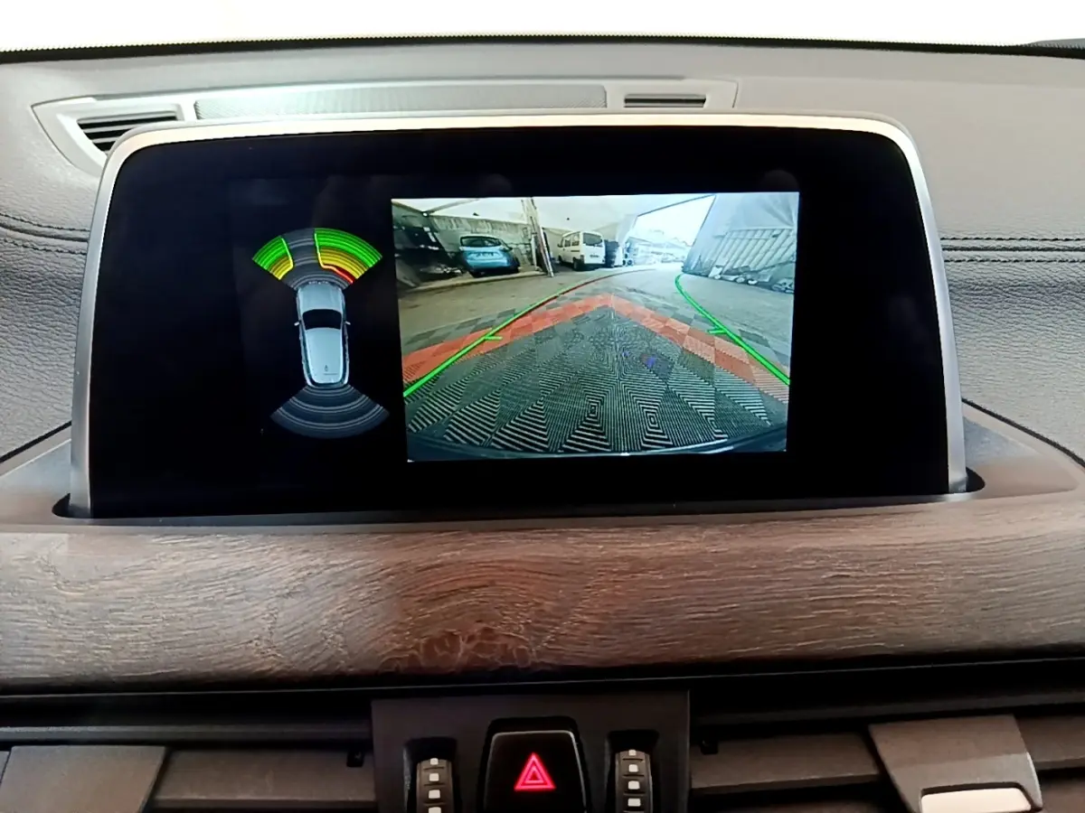 Écran tactile intérieur montrant la caméra de recul et l’aide au stationnement du BMW X2 bleu.