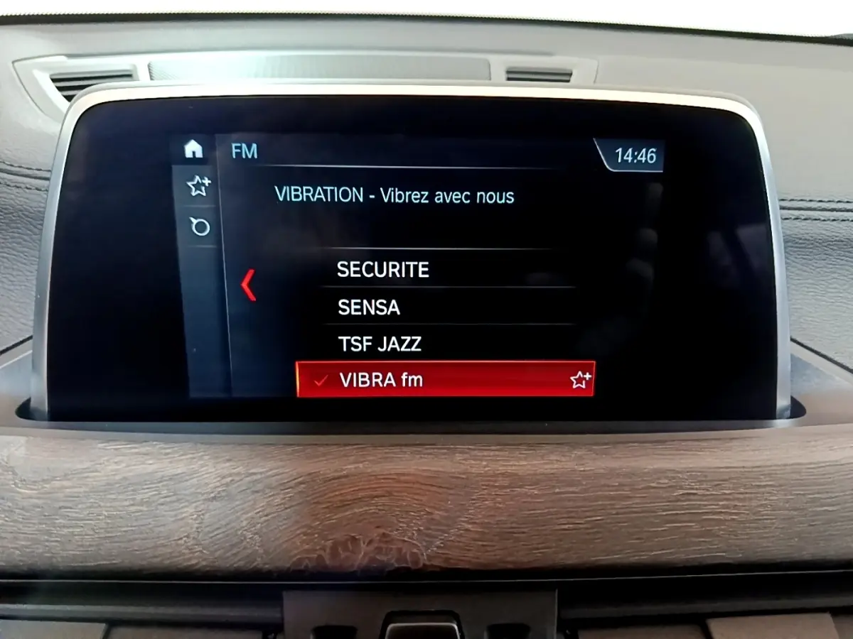 Écran tactile central du tableau de bord avec affichage radio FM dans une BMW X2 bleu 2019.