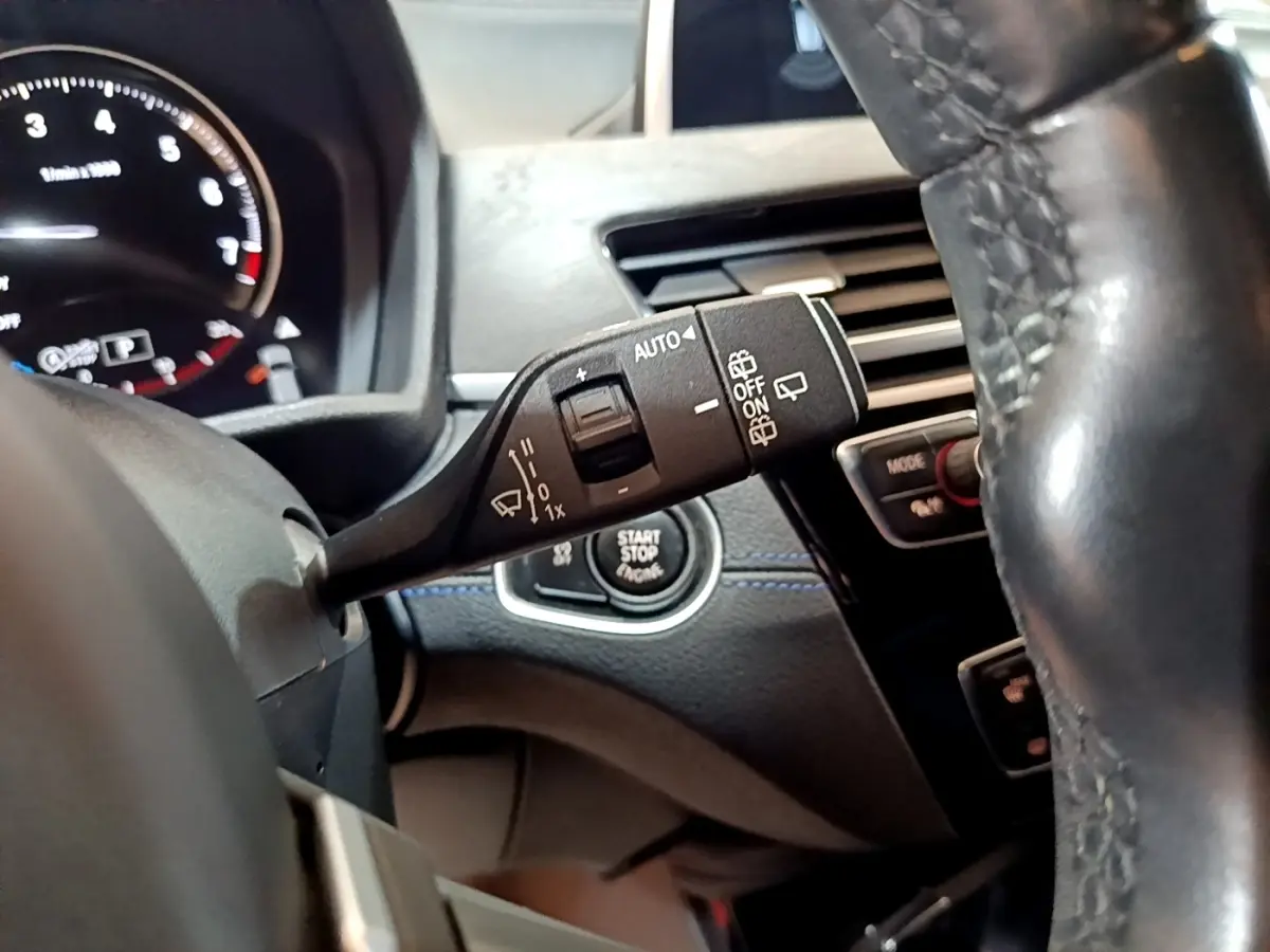 Gros plan sur la manette d’essuie-glace et le bouton start/stop du tableau de bord d’une BMW X2 bleu 2019.