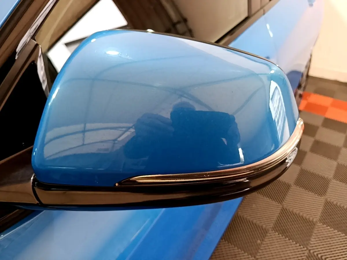 Rétroviseur côté gauche bleu brillant de la BMW X2 sDrive20i M Sport DKG7 avec clignotant intégré, vue rapprochée.