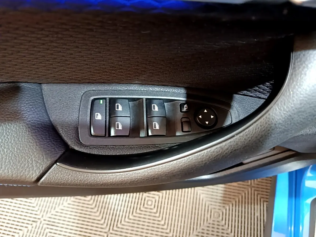 Gros plan sur les commandes des vitres et rétroviseurs côté conducteur d’une BMW X2 bleu sDrive20i M Sport 2019.