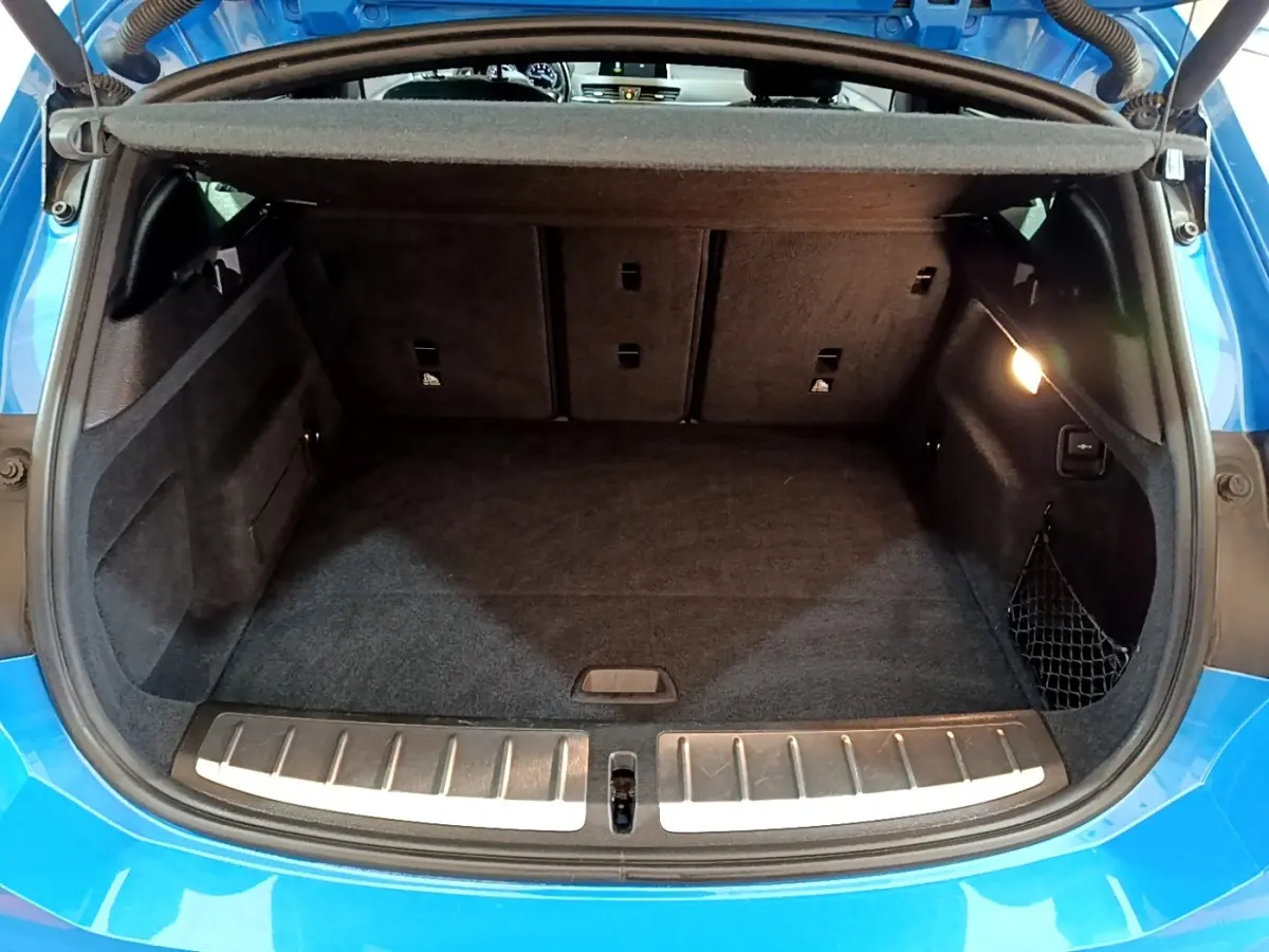 Coffre ouvert d'une BMW X2 bleu, vue arrière montrant l'espace de chargement et la banquette rabattable.