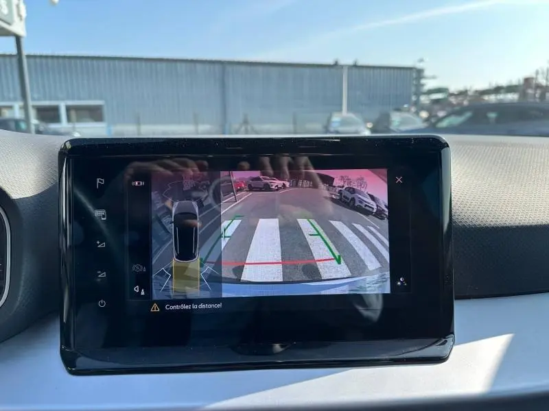 Écran intérieur montrant la caméra de recul du SEAT Arona blanc Candy avec toit noir, vue arrière en stationnement.