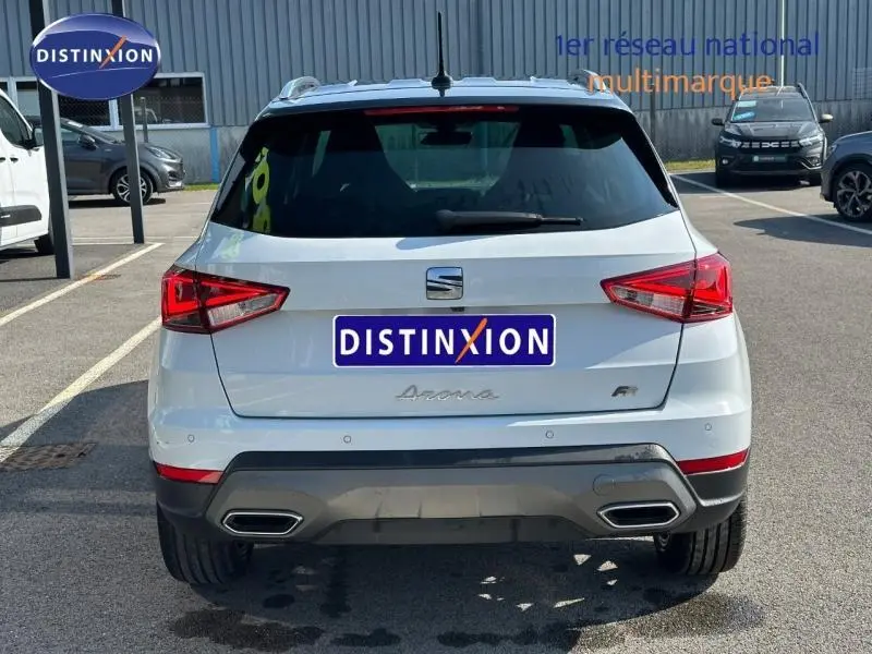 Vue arrière d'un SEAT Arona blanc Candy avec toit noir Minuit, version FR, garé en extérieur sur parking.