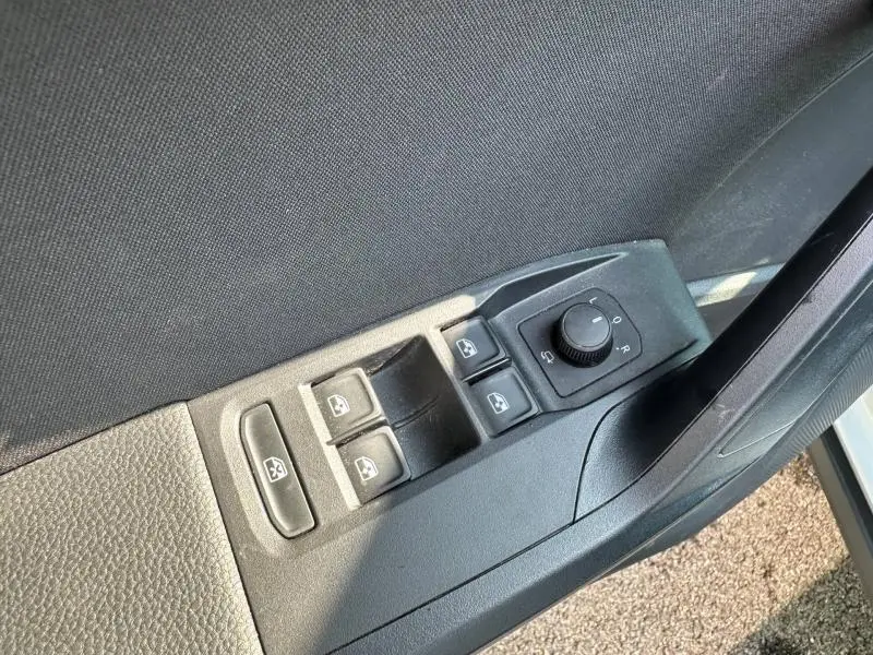 Gros plan sur les commandes des vitres et des rétroviseurs côté conducteur d'un SEAT Arona 2025 blanc avec toit noir.