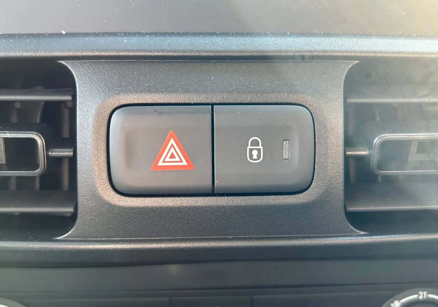 Gros plan sur les boutons de verrouillage centralisé et warning du tableau de bord du DANGEL Partner gris Artense 2025.