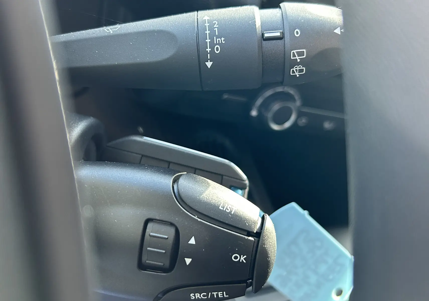Gros plan sur les commandes au volant du Peugeot Partner Dangel gris Artense, montrant les boutons de contrôle multimédia et essuie-glace.