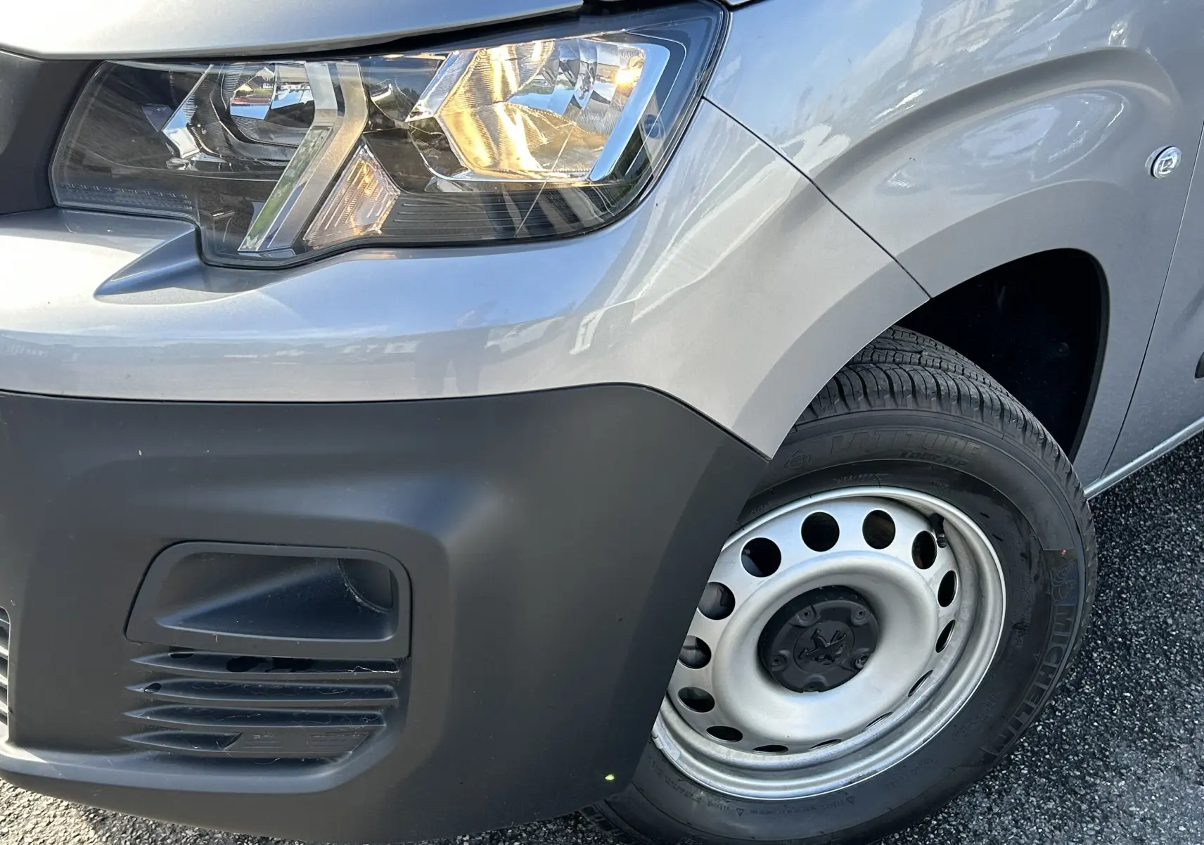 Gros plan sur l'avant droit gris Artense du DANGEL PARTNER 4x4 avec phare allumé et jante acier simple.