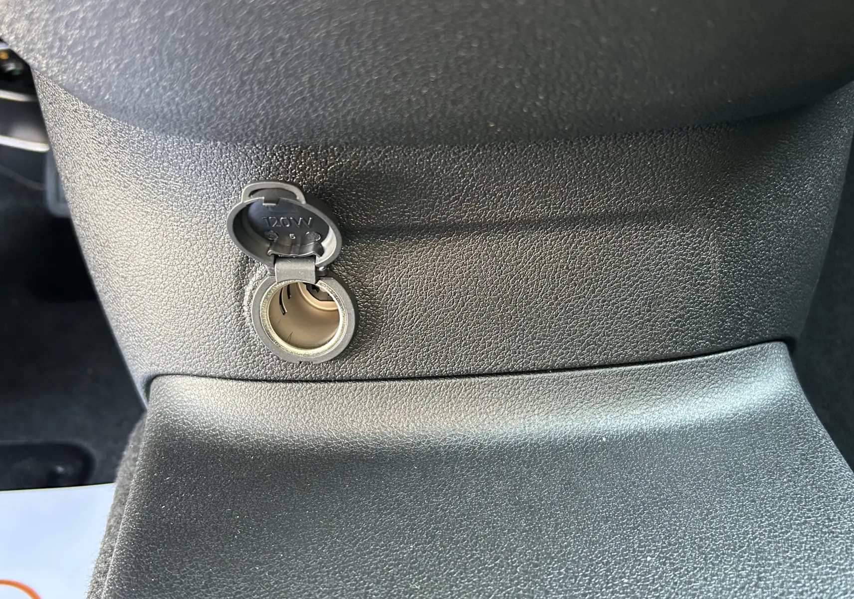 Prise 12V ouverte en gros plan sur la console centrale intérieure du Peugeot Partner Dangel gris Artense 2025.