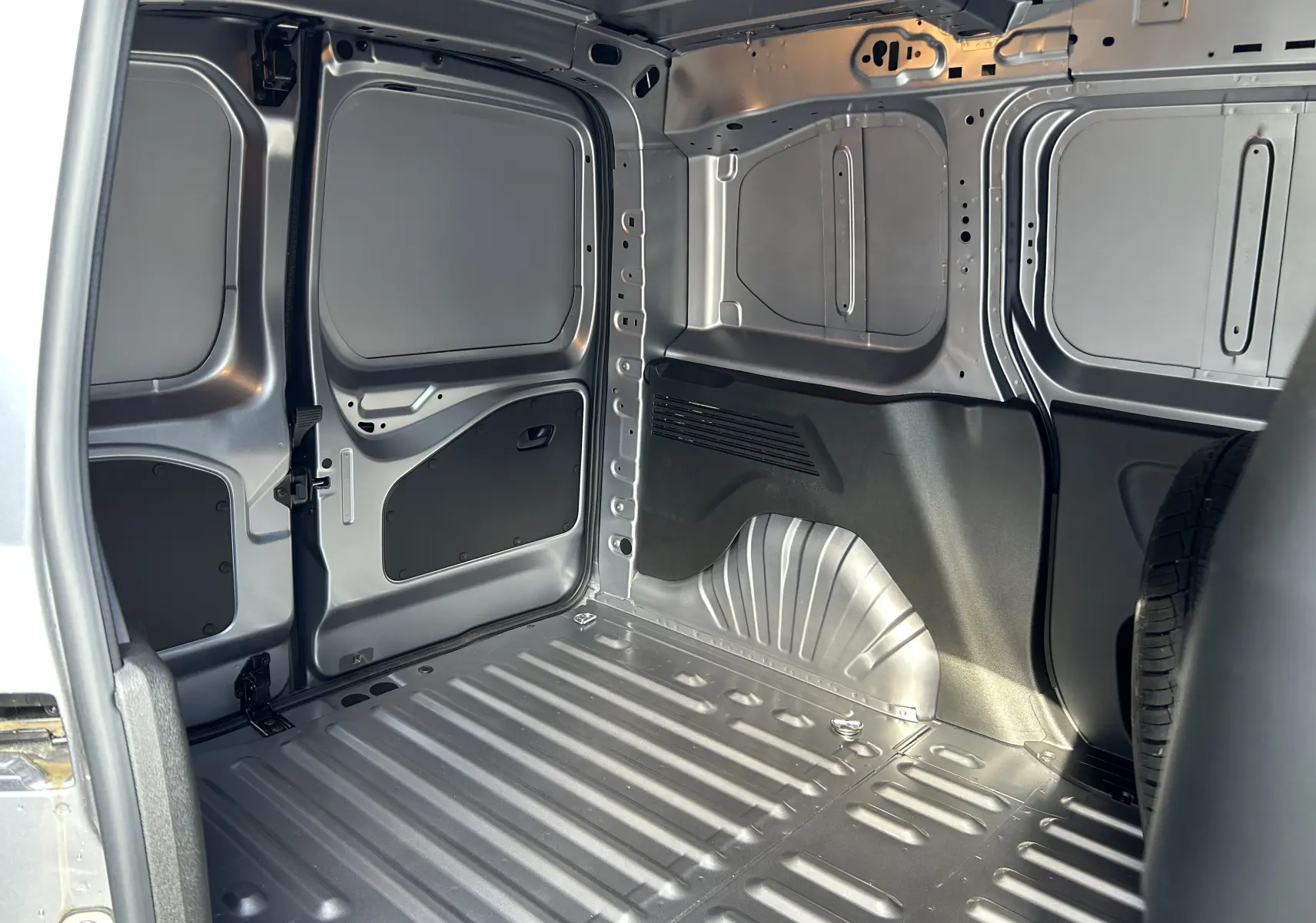 Intérieur du coffre gris Artense du DANGEL PARTNER 4x4, vue côté gauche montrant la structure métallique et la roue de secours.