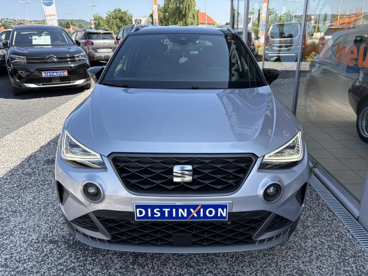 Vue de face d'une SEAT Arona 2024 gris clair avec calandre noire et projecteurs LED marqués, en concession.