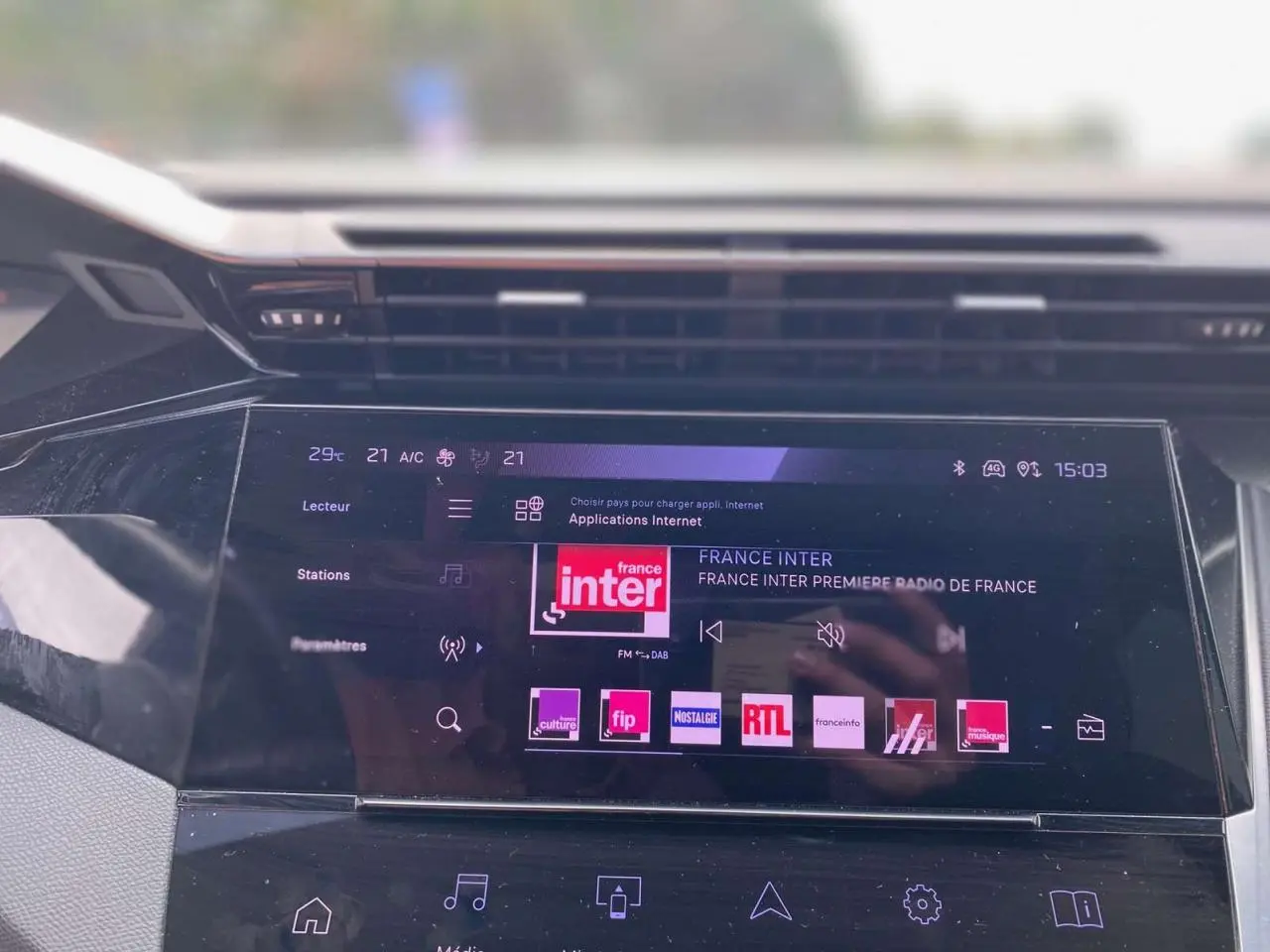 Écran tactile central de la Peugeot 308 2023 affichant les stations radio, vue intérieure frontale.