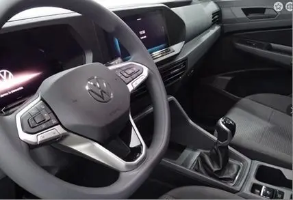 Vue intérieure du Volkswagen Caddy Maxi 2025, tableau de bord et volant multifonction avec boîte manuelle, finition noire moderne.