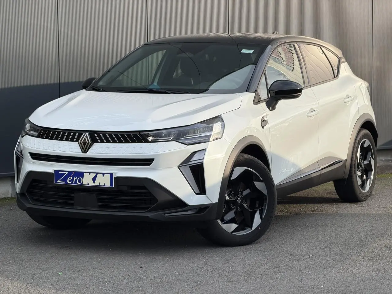 Renault Captur 2025 blanc nacré et noir étoile vu en 3/4 avant droit avec jantes noires distinctives.