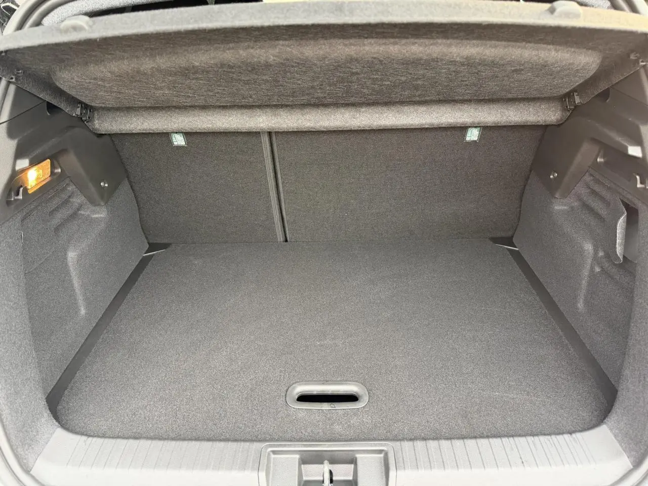 Coffre spacieux du Renault Captur 2025 en vue intérieure, avec revêtement gris foncé et éclairage latéral.
