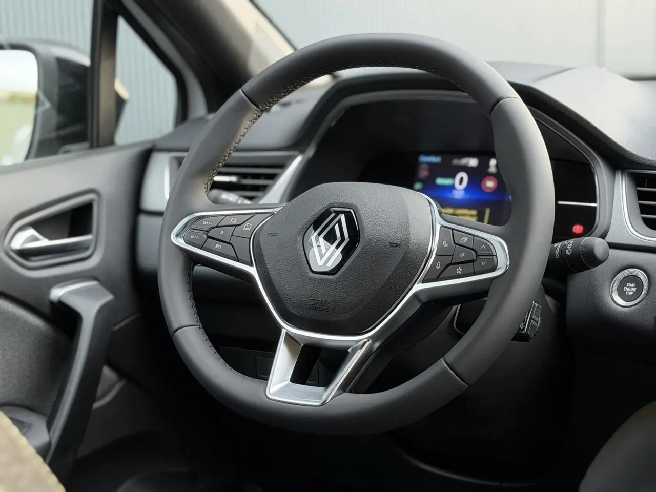 Vue rapprochée du volant noir et du tableau de bord numérique du Renault Captur blanc nacré 2025 en intérieur.