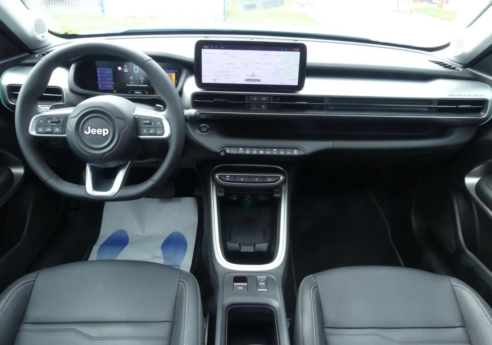 Vue intérieure avant du Jeep Avenger 2024, tableau de bord noir avec écran tactile central et volant multifonction.