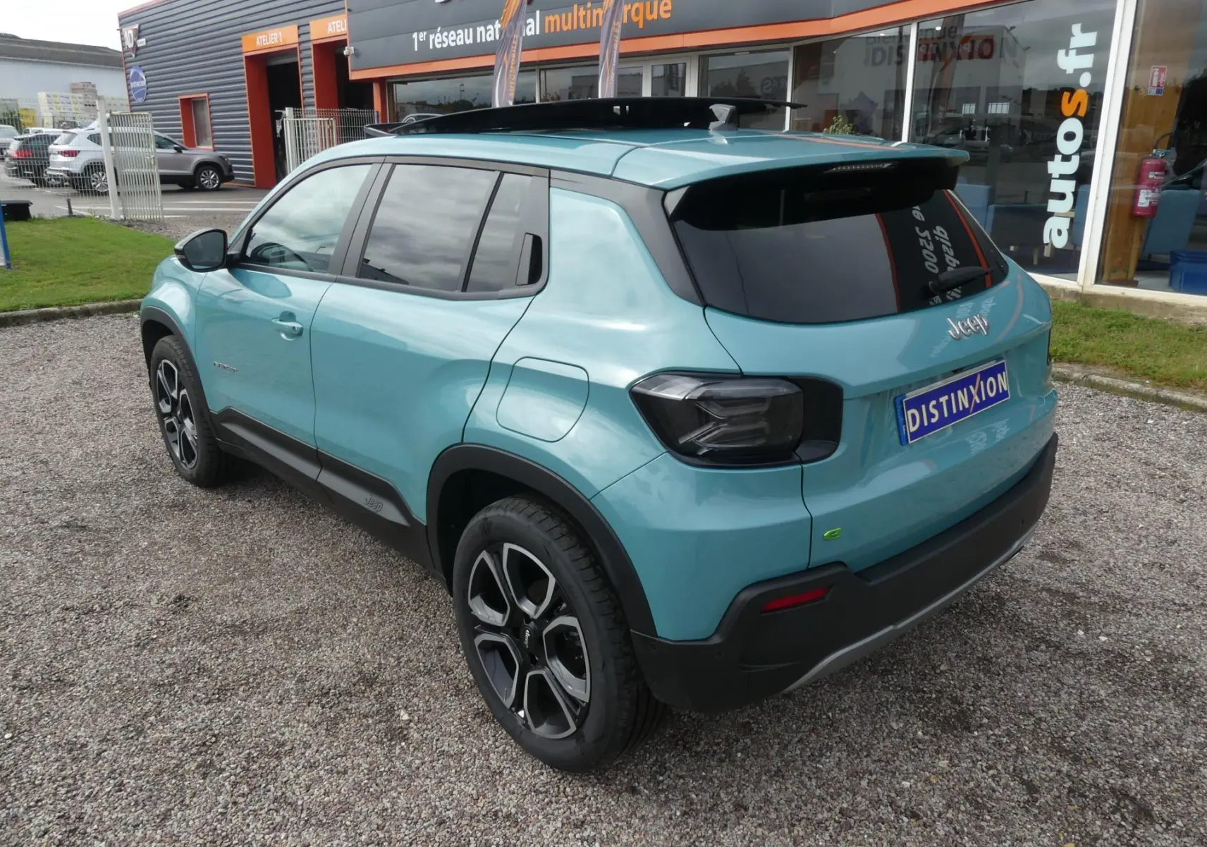 Vue 3/4 arrière droite d'un Jeep Avenger bleu métallisé avec toit noir et vitres arrière surteintées.