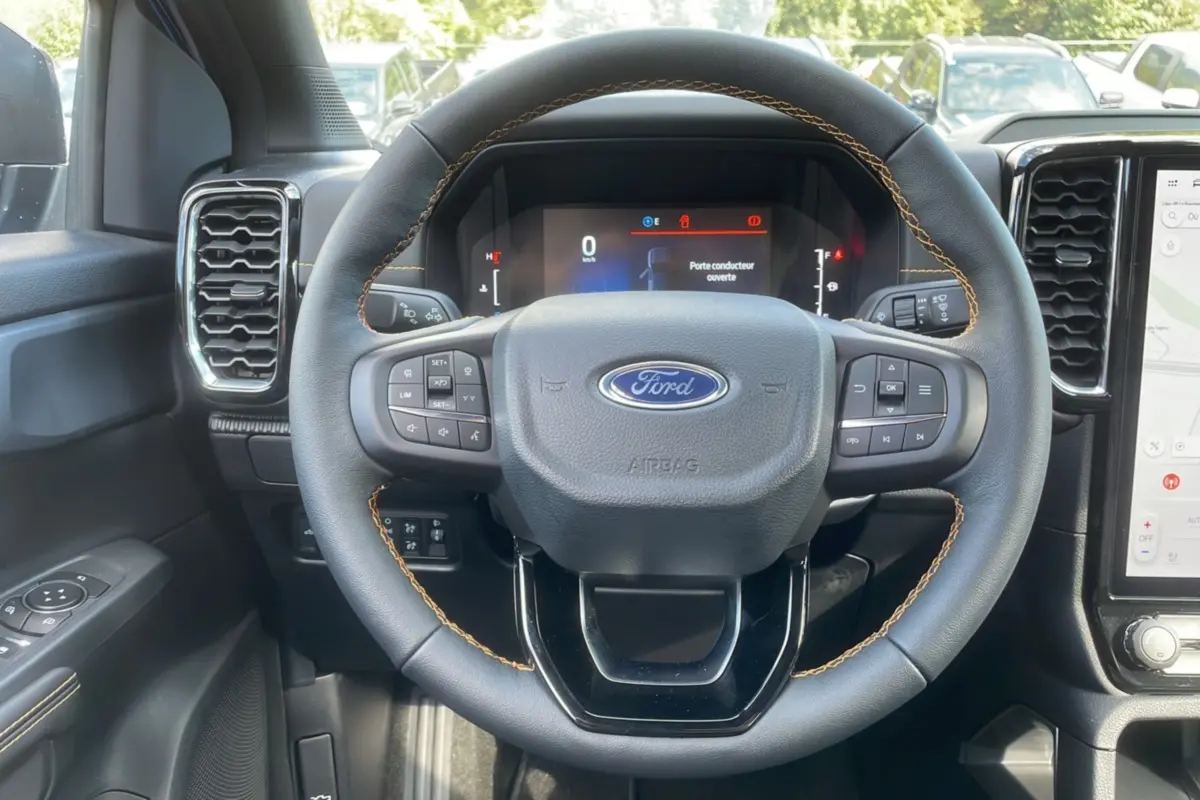 Vue intérieure centrée sur le volant cuir noir avec surpiqûres jaunes du Ford Ranger Wildtrak 2025.