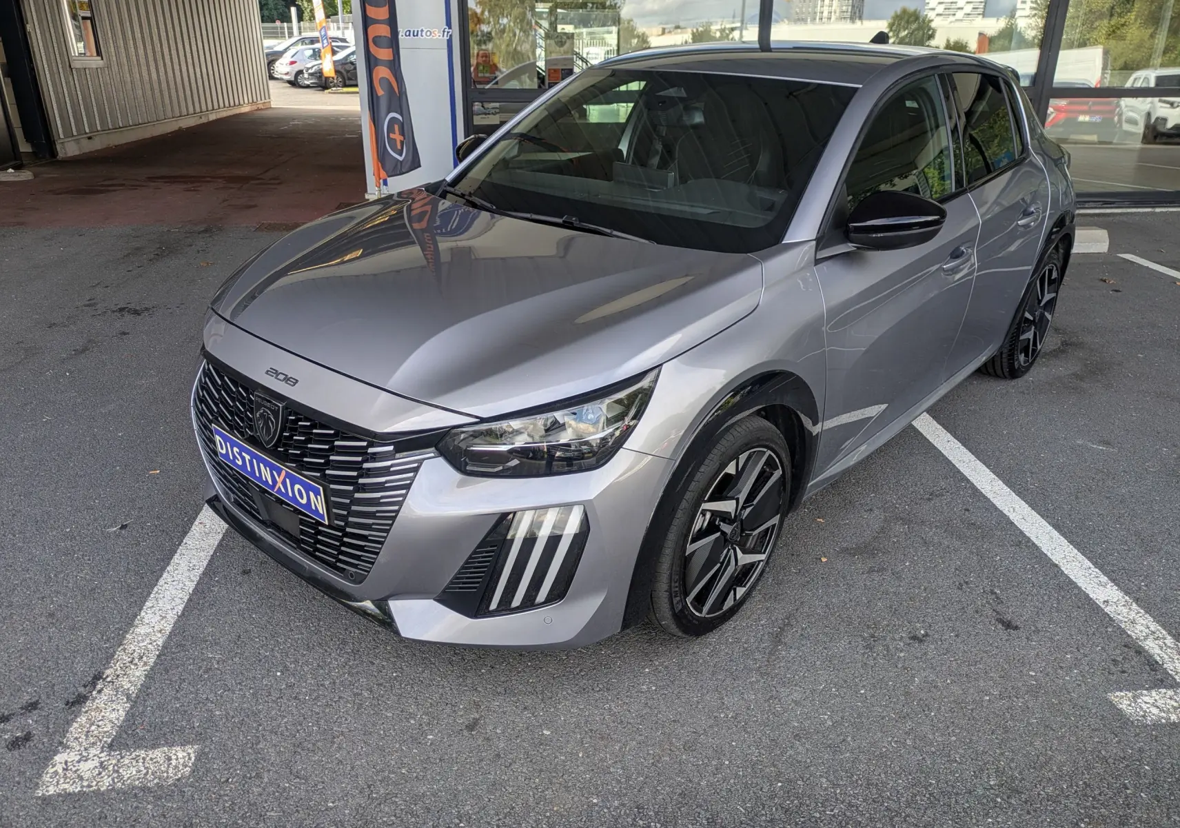 Peugeot 208 Hybrid 145 gris Artense vue 3/4 avant droit, avec calandre noire et jantes alliage 17 pouces bicolores.